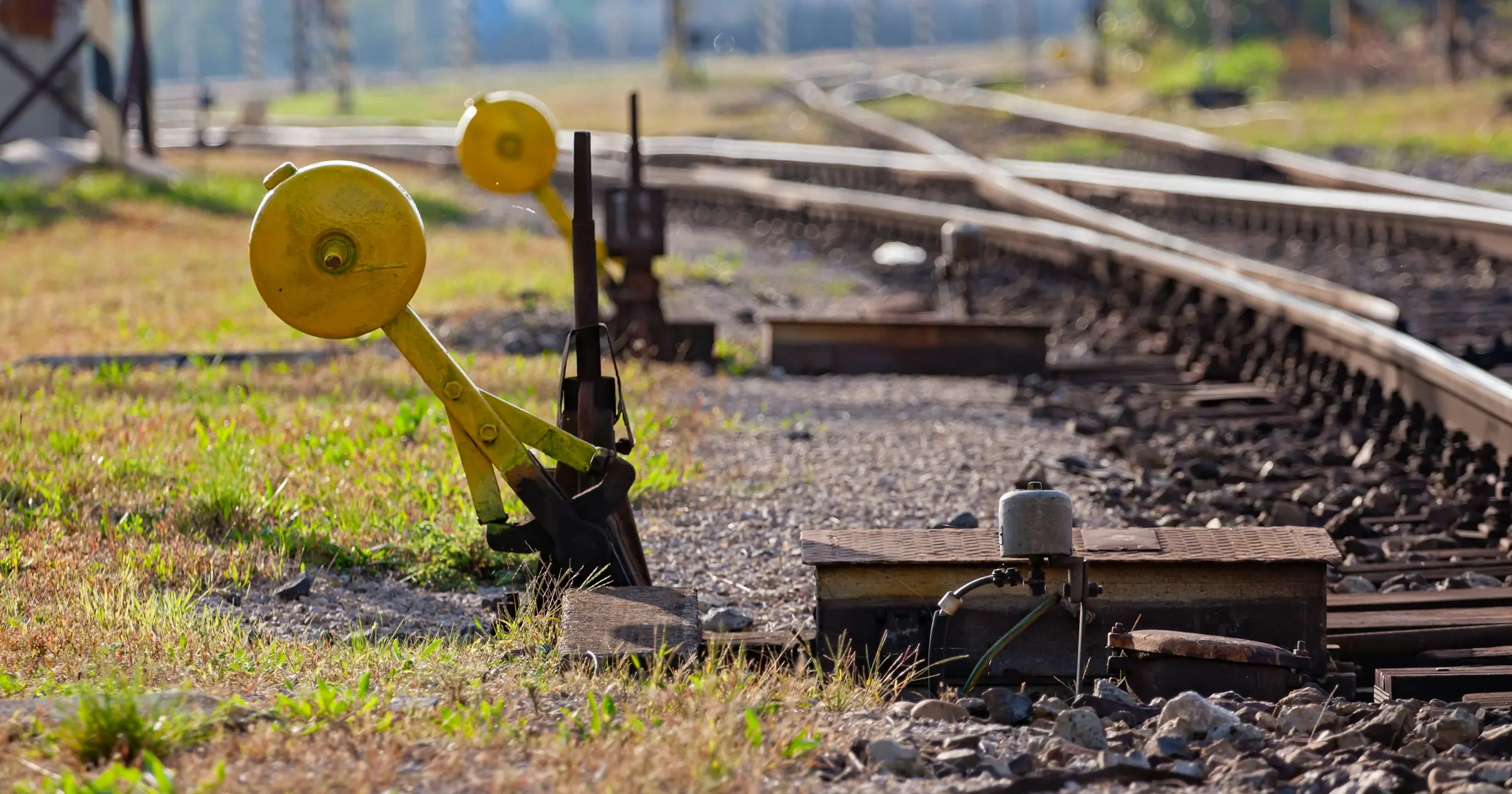 Yellow railway switch levers beside train tracks that branch off in different directions.