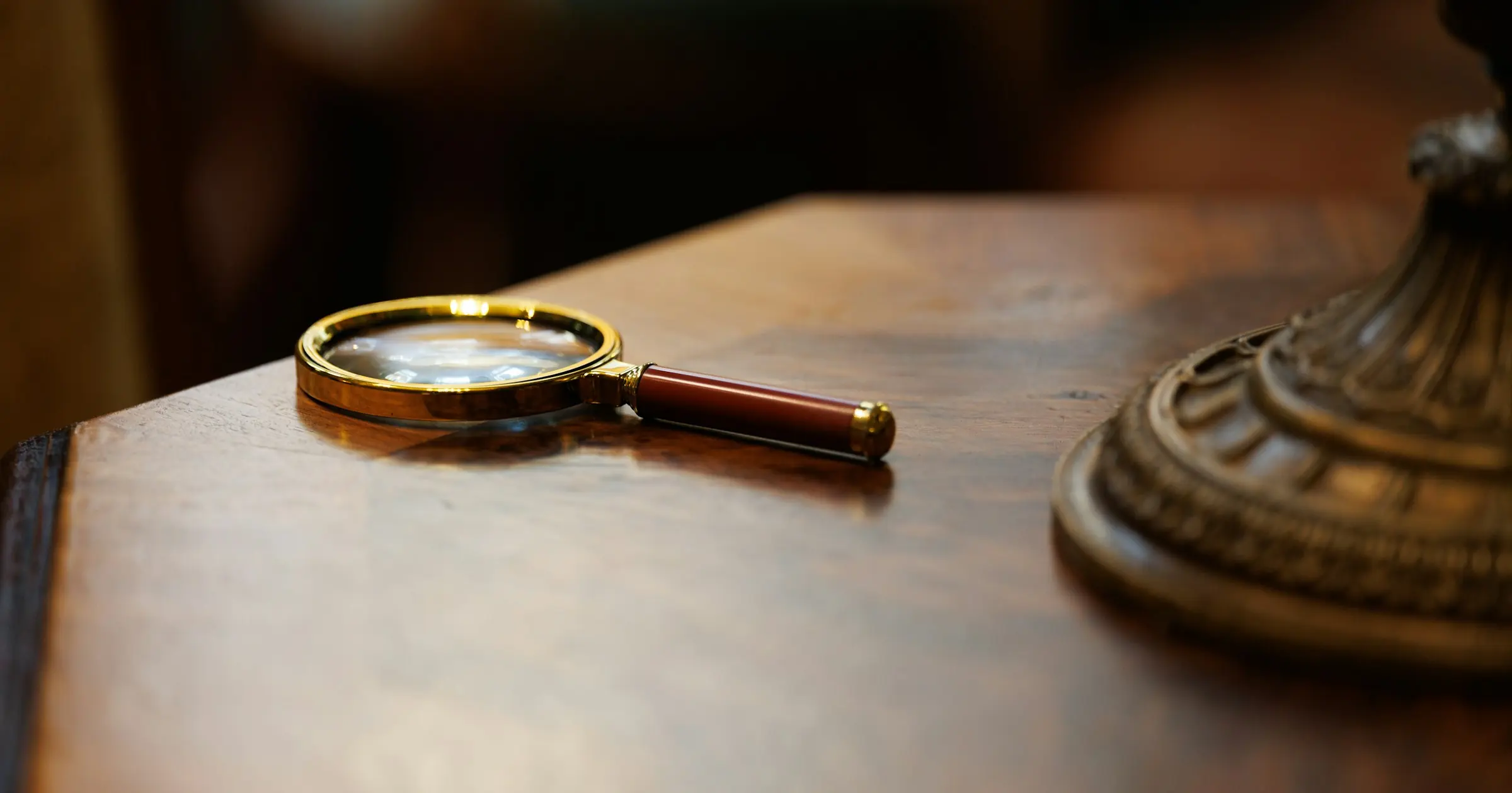Brass magnifying glass lying on a polished wooden desk