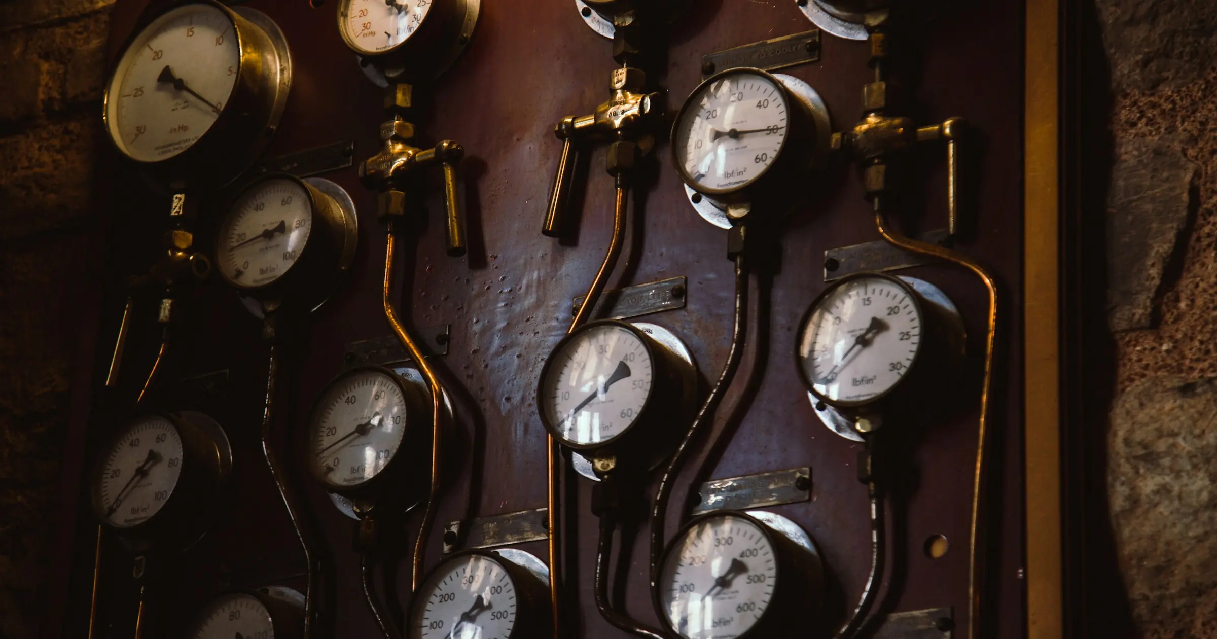 Wall panel of vintage pressure gauges connected by copper pipes