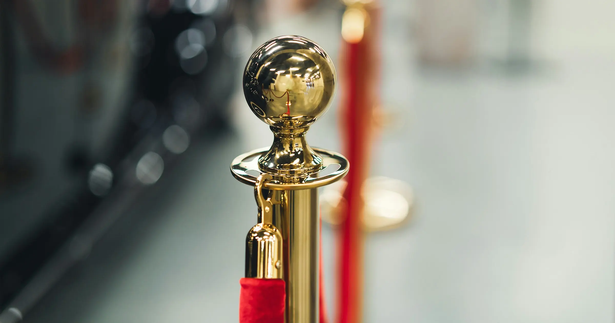 Gold stanchion post holding a red velvet rope barrier