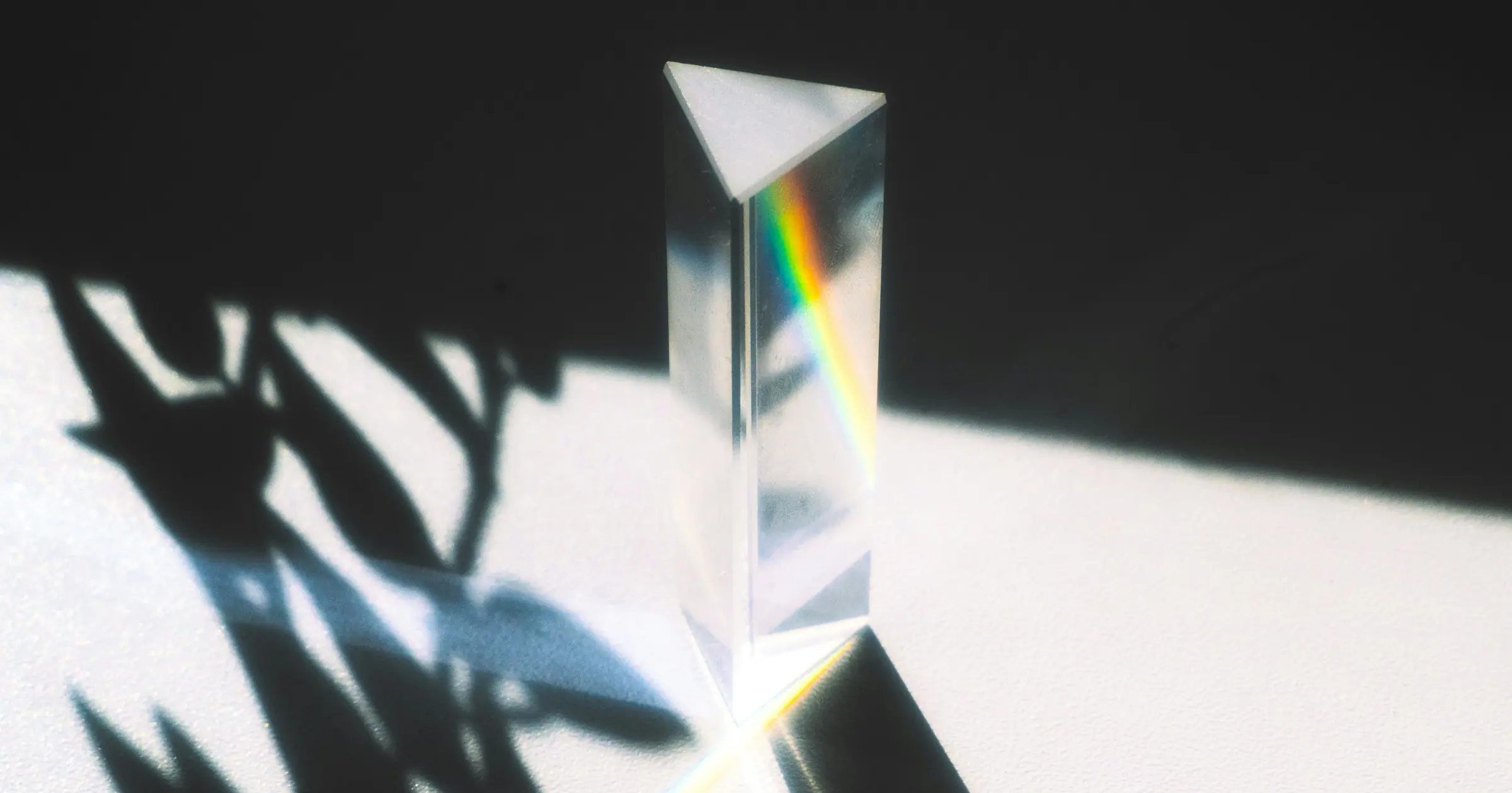 Glass prism standing in a patch of sunlight, splitting the light into a rainbow