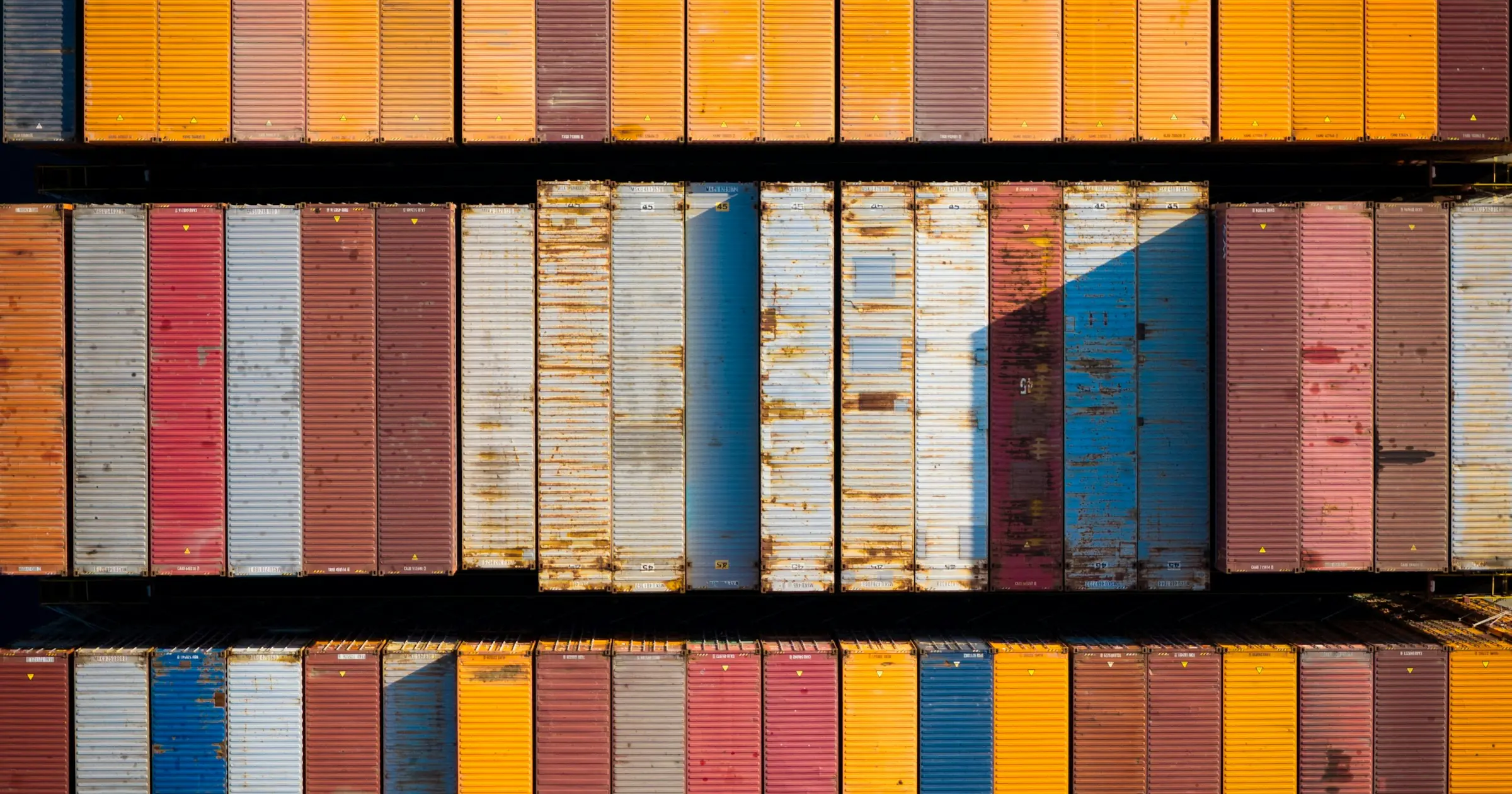 Rows of colorful shipping containers stacked side by side, seen from above.