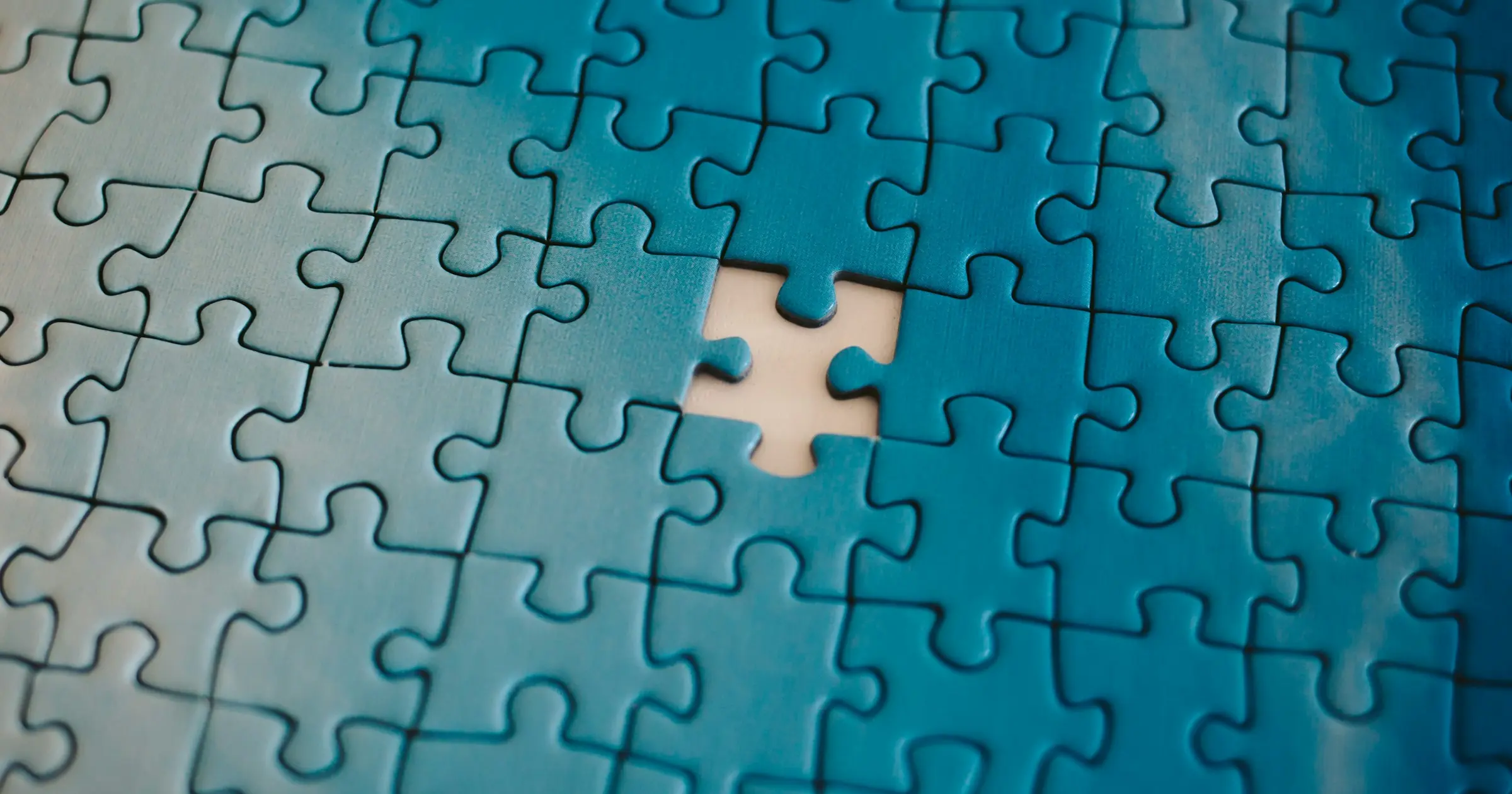 A blue jigsaw puzzle with one piece missing near the middle