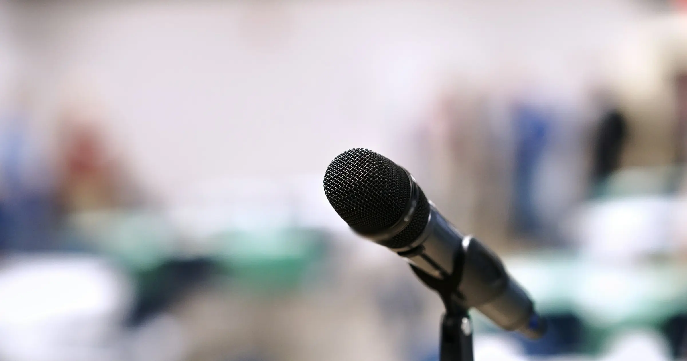 Microphone on a stand in front of a blurred conference room