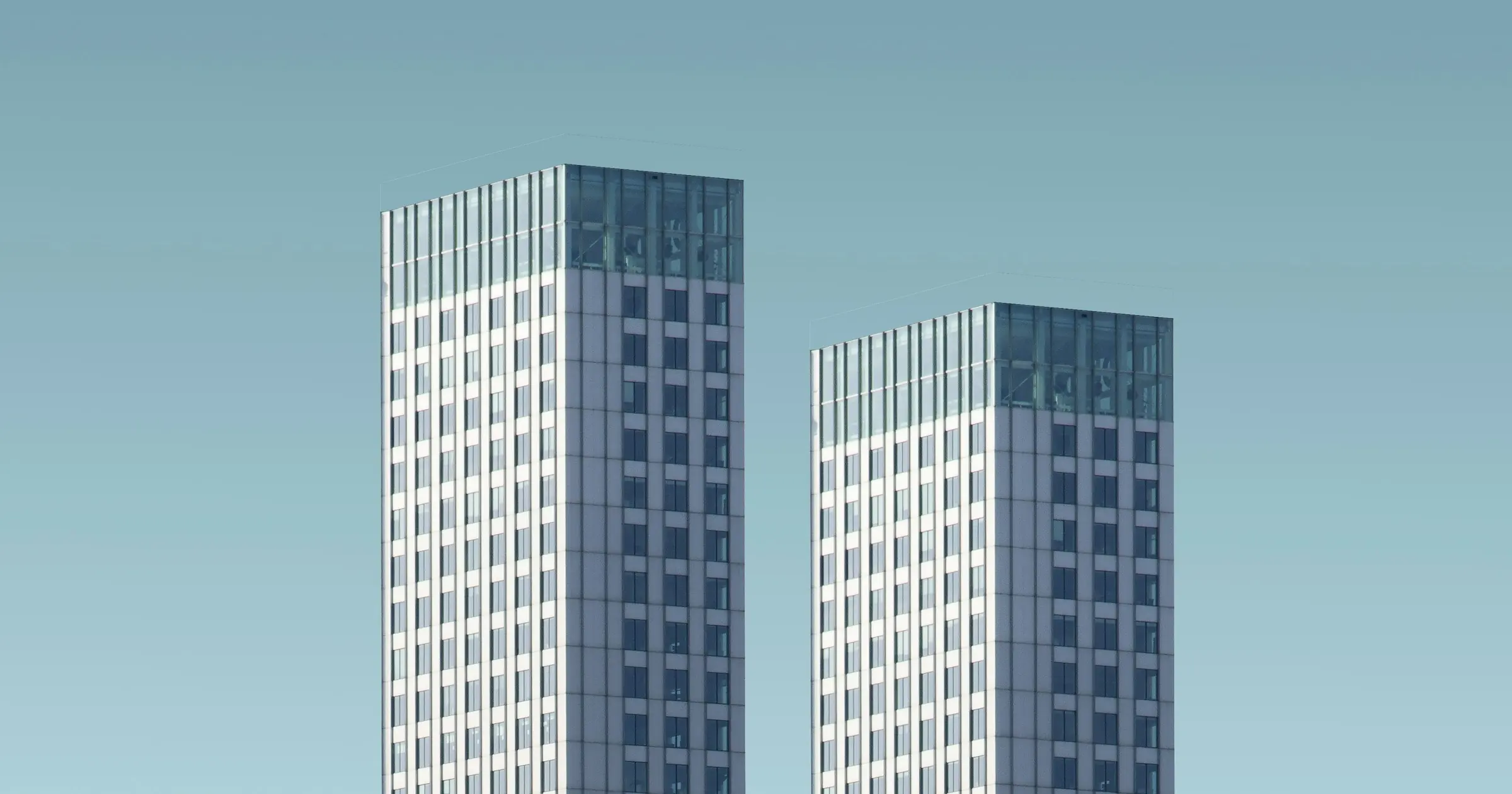 Two matching high-rise towers side by side against a teal sky