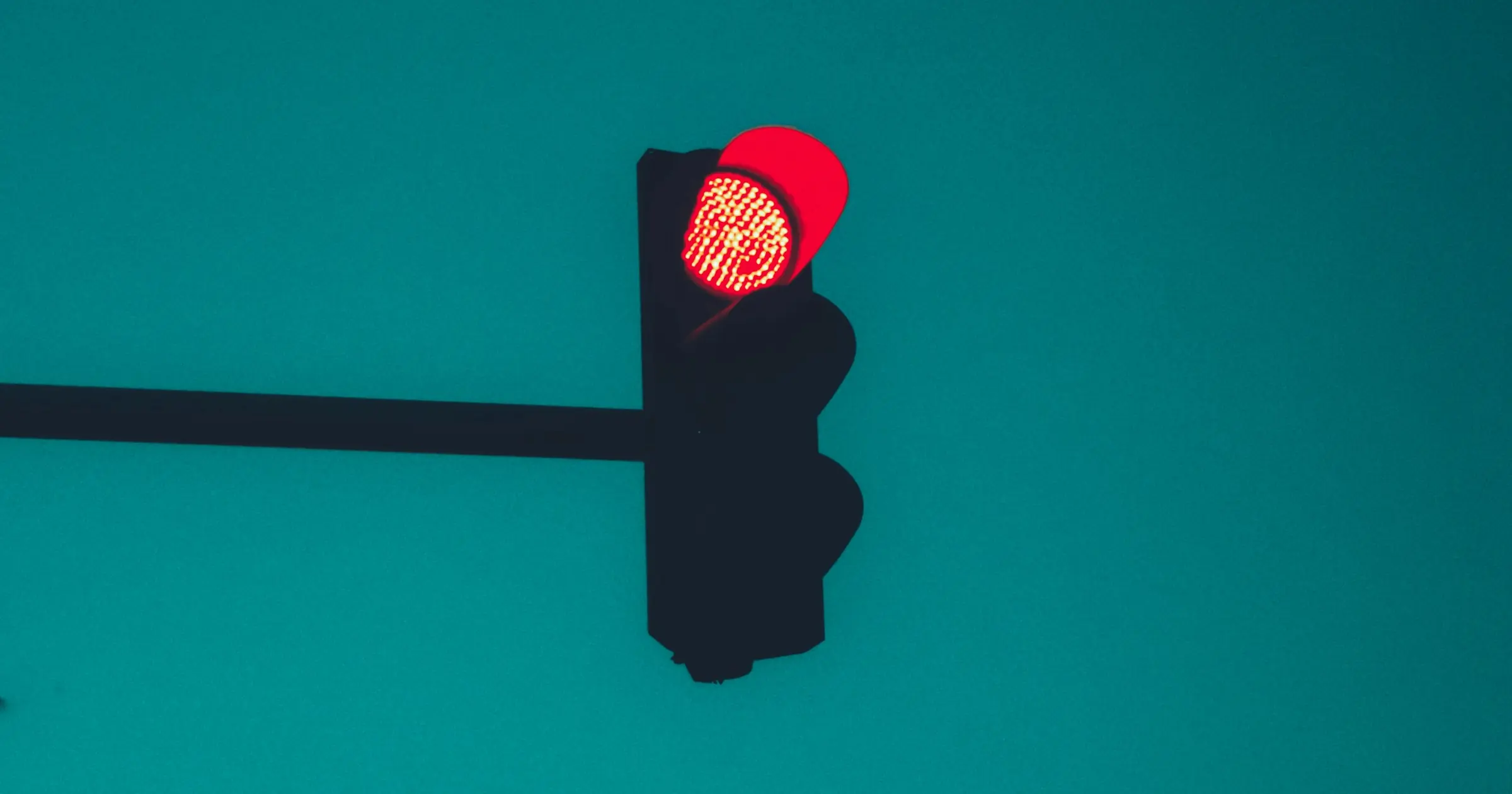 Traffic light showing red against a plain teal sky