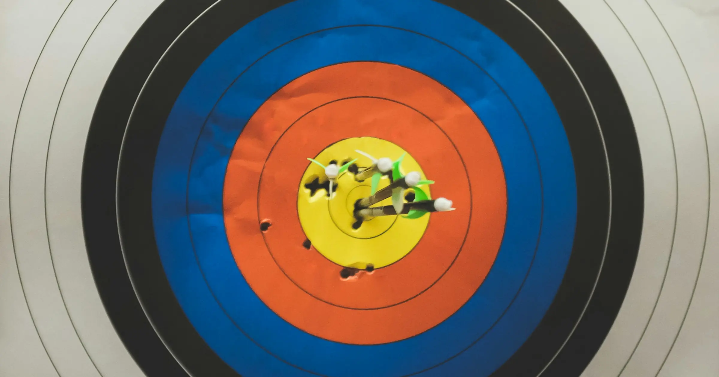 Close-up of an archery target with a cluster of arrows in the yellow bullseye