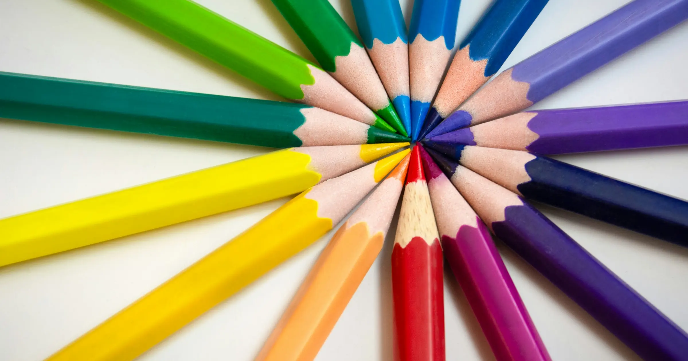 Colored pencils of many different colors arranged in a circle with their tips meeting
