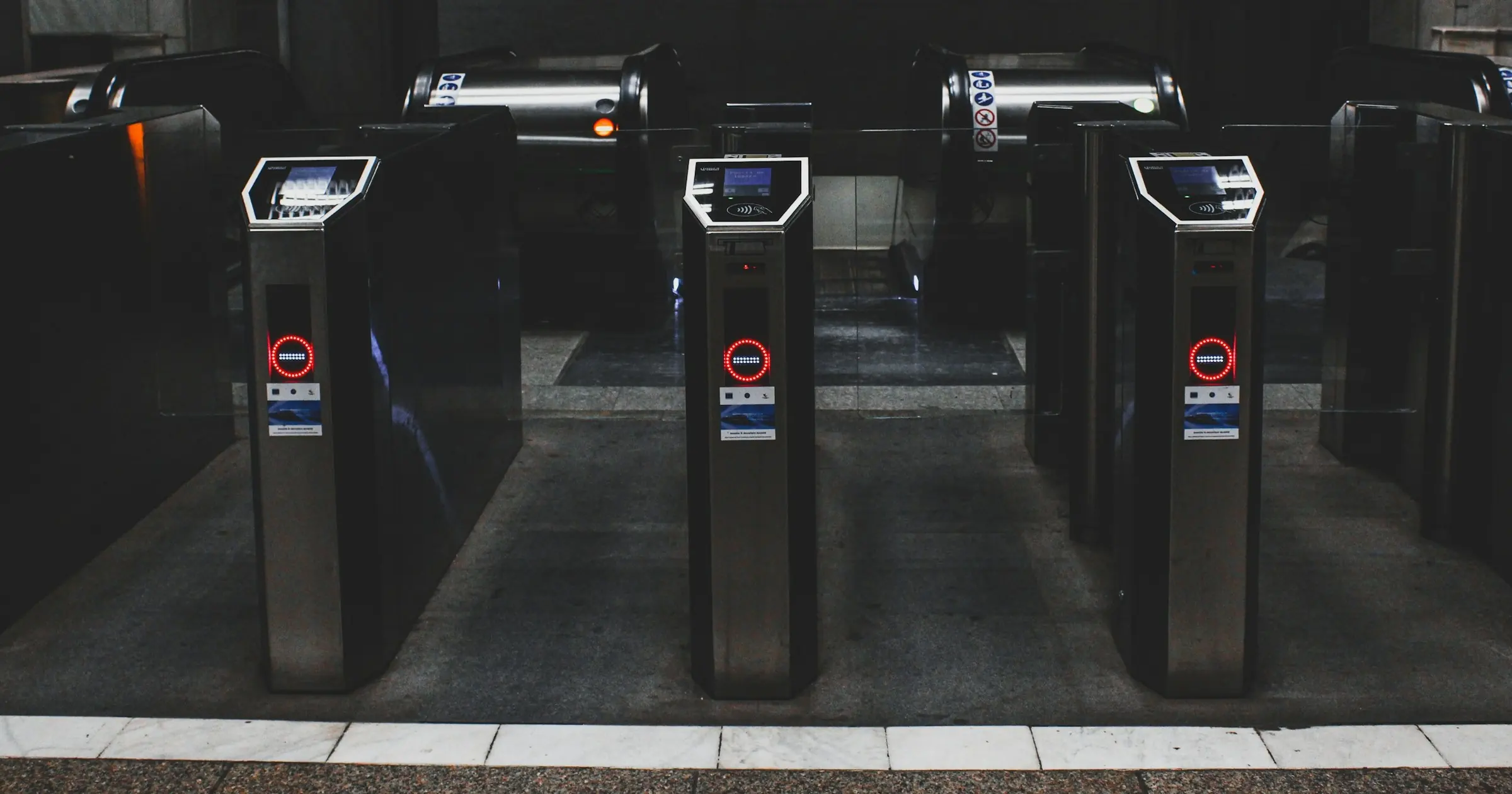 Row of closed subway turnstiles with red no-entry lights in a dark station