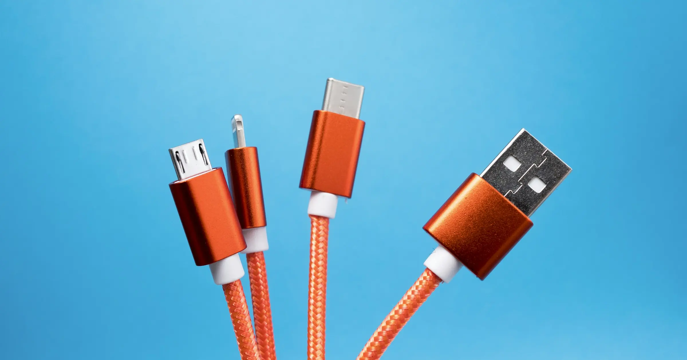 An orange braided cable splitting into four different connector heads against a blue background