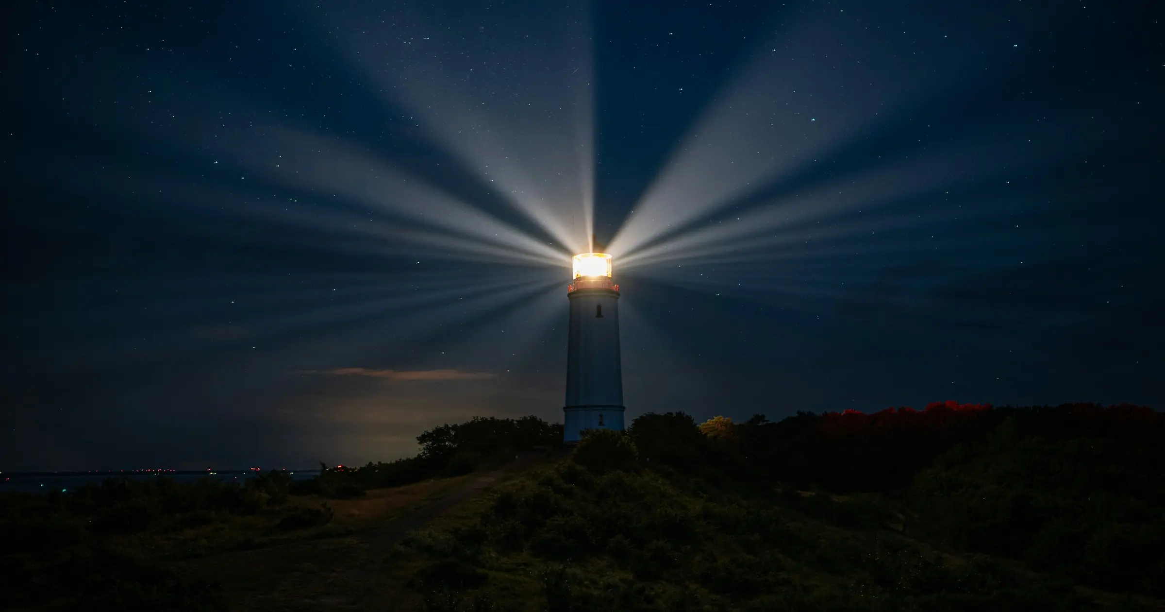 A lighthouse sending beams of light across a starry night sky